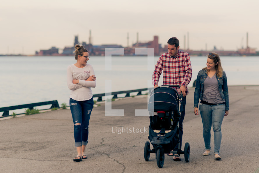 family walking along a harbor pushing a stroller 