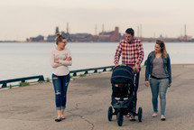 family walking along a harbor pushing a stroller 