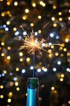 Sparkler in a champagne bottle with bokeh lights