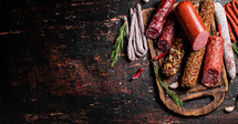 Assortment of various aromatic salami sausages. Against a dark background. High quality photo