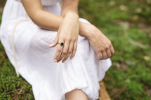 a young woman in a dress sitting on mossy ground 