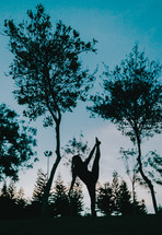 silhouette of a dancer stretching in a forest 
