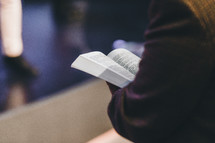 Close up of a person holding an open Bible during a service.