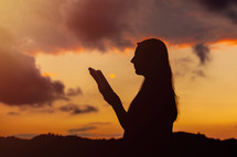 Girl silhouette, reading the bible with beautiful dramatic sky background