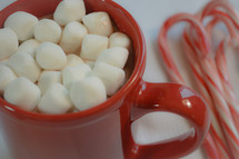 marshmallows in a red mug and candy canes 
