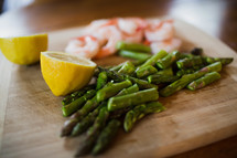 lemons, asparagus, and shrimp on a wood cutting board