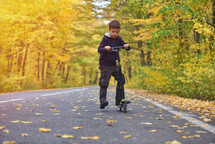 boy riding scooter, outdoor in autumn environment on sunset warm light