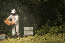 Beekeeper assembling a bee hive full of honey bees, beekeeping suit