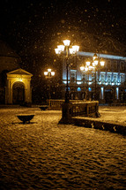 falling snow and street lamps in a city 