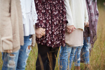 a group of young women in a field holding hands 