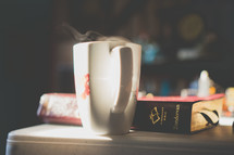 steam from a coffee mug and a Bible on a table 