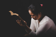 Woman praying with hands on her Bible