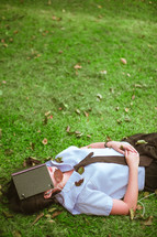a girl sleeping in the grass with a book covering her face 
