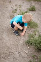 a toddler boy playing in sand 