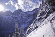 Hiking through snowy mountains on a steep, narrow trail.