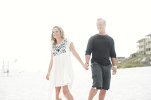 couple walking on a beach holding hands 