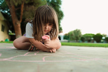 a girl child coloring with sidewalk chalk 