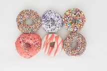 rows of sprinkled donuts on a white background 