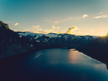 aerial view over a mountain lake and snow capped mountain at sunset 