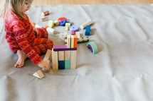 a toddler girl playing with building blocks 