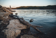 person standing on a rocky river shore 