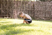boy playing in a sprinkler 