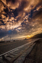 asphalt on a road and the sun setting behind a mountain 