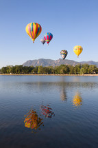 Colorful Hot air balloons flying over a Colorado Lake with the mountains in the distance
