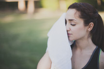 Woman wiping the sweat from her face with a towel.