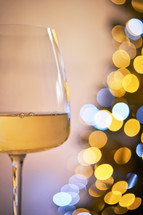 Wine glass with gold and white bokeh lights in the background
