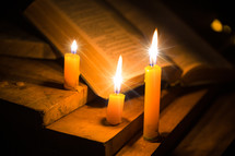 Open Bible on rustic wood table and candles