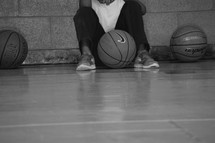 An African American boy waiting on the sidelines of a basketball court 