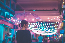 a woman carrying an umbrella outdoors at night 
