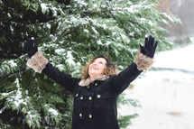 a woman standing in the snow with raised hands 