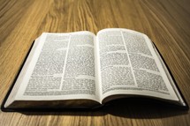 An open bible on a wooden table