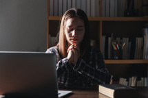 Woman praying with Bible and computer
