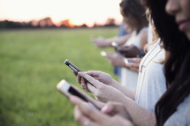 row of young adults texting on a cellphone 