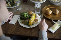 A person seated at the dinner table with a plate of food.