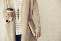woman holding a paper coffee cup and Bible 