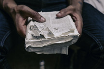 hands of a man holding an old worn and torn Bible 