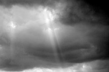 Ray of light through stormy clouds in a dark sky.