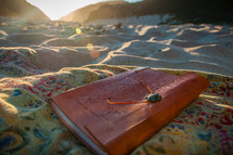journal on a blanket in the sand 