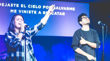 people on stage singing at a worship service