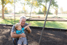 grandfather and grandson swinging on a swing 
