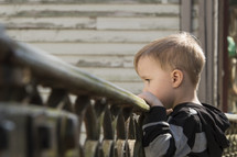 a toddler boy looking over a railing 
