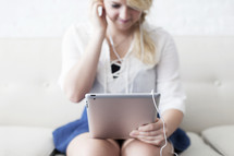 woman with earbuds looking at an iPad 