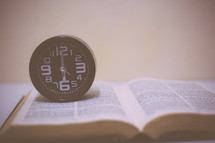 wall clock on an open Bible 