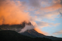 mountain peak in the clouds at sunset 