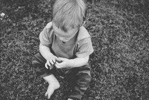 an infant sitting in grass 