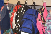 book bags hanging on hooks in an elementary school classroom 